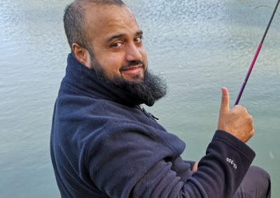 Asian man giving thumbs up after catching his first fish