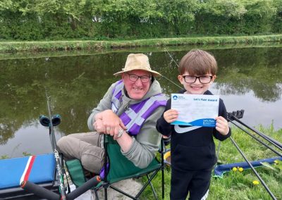 Angling coach and smiling young student on canal bank