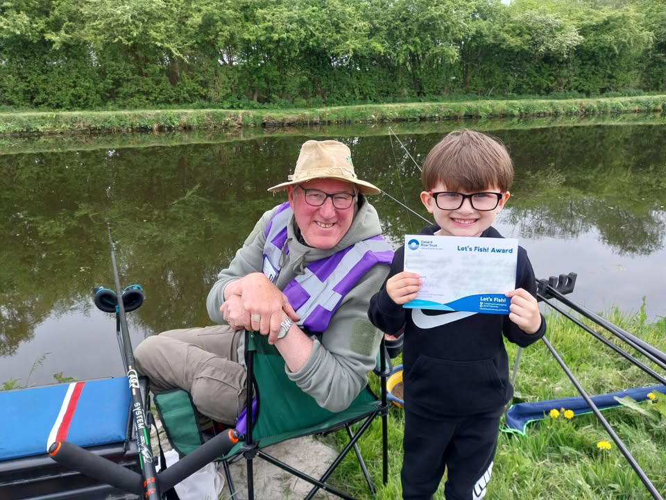 Angling coach and smiling young student on canal bank
